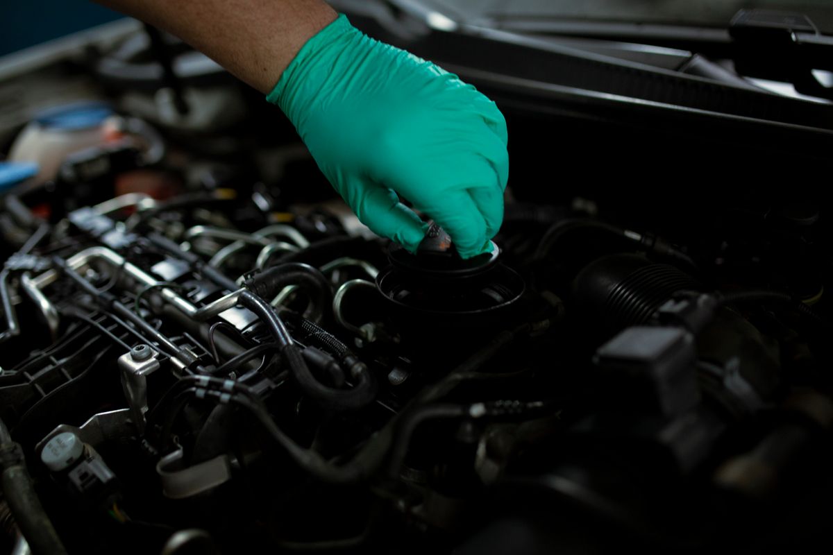 Mechanic in gloves changing engine oil, stock photo